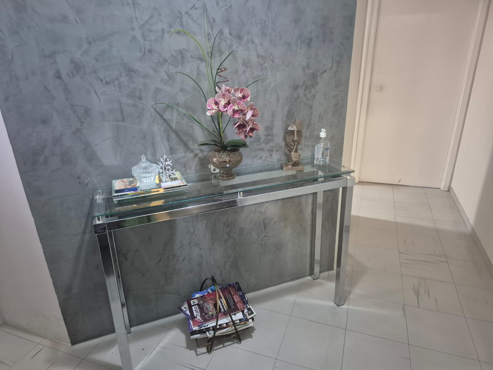 Hall de entrada com aparador de vidro, orquídea e parede marmorizada
