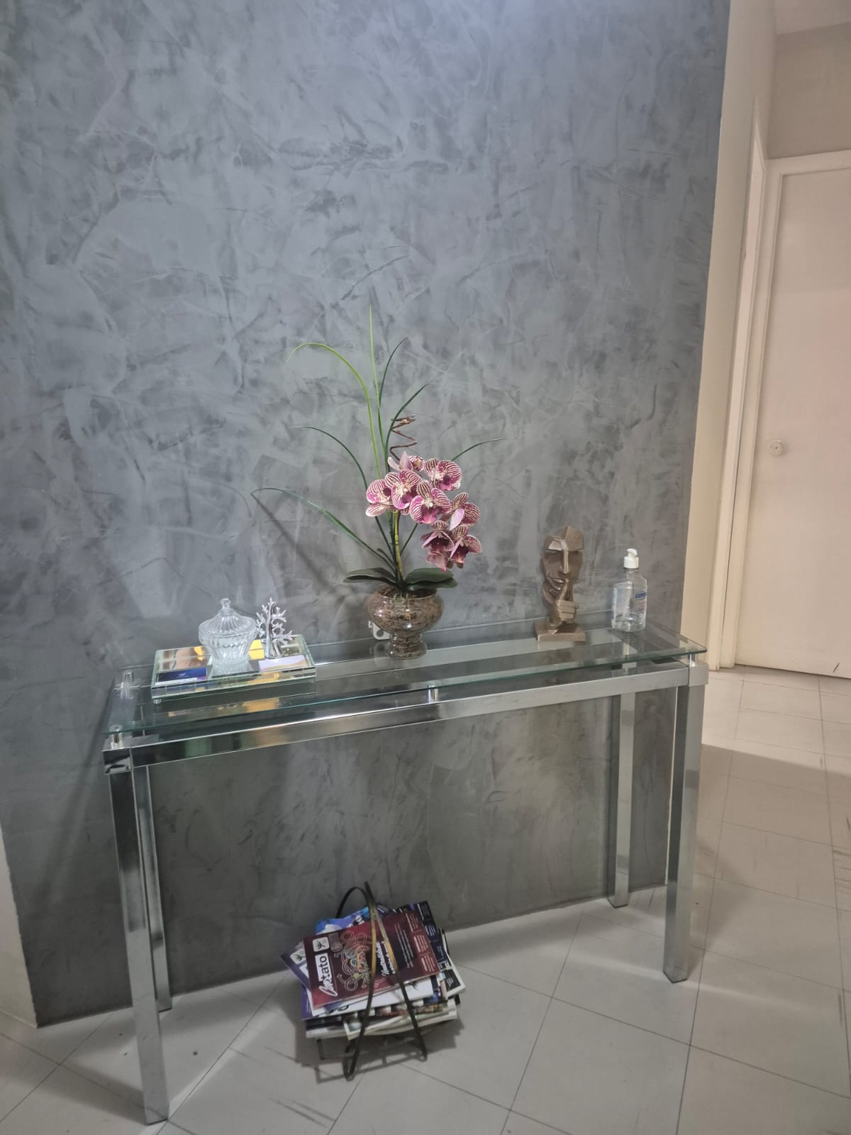 Aparador de vidro com orquídea e objetos decorativos