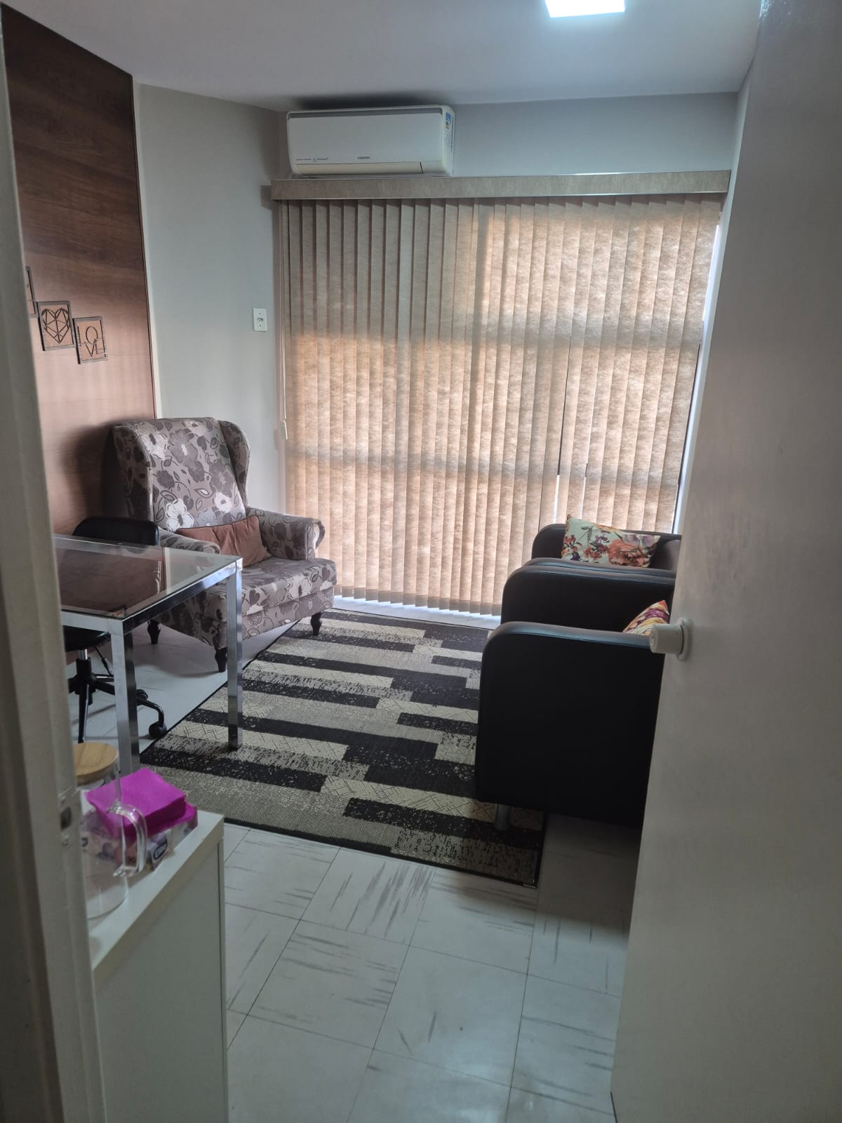 Consultório visto a partir da porta, com poltronas e luz natural