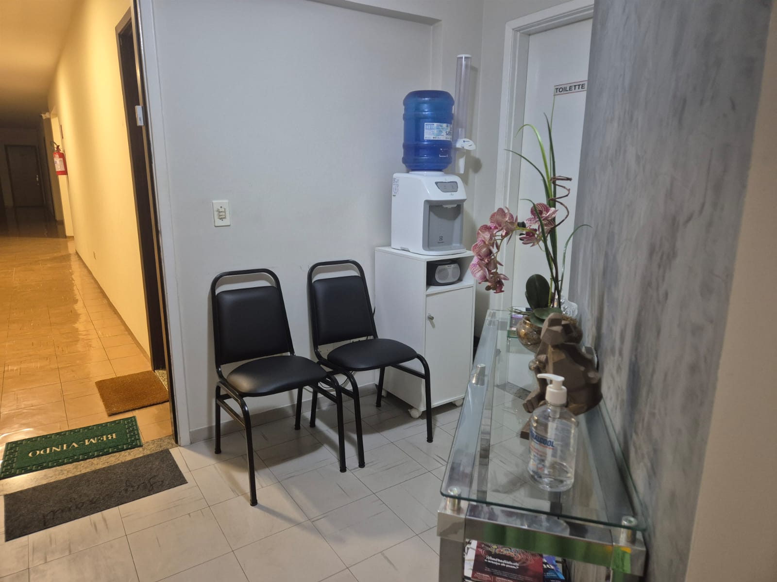 Recepção com cadeiras, bebedouro e corredor de entrada